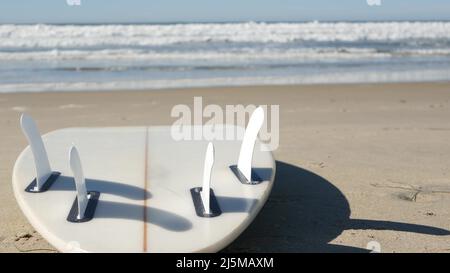 Surfboard per il surf sdraiato sulla spiaggia di sabbia, costa californiana, USA. Onde oceaniche e tavole da surf bianche o paddleboard. Longboard o sup per la ricreazione di sport acquatici con acqua di mare. Cinematografia senza giunture. Foto Stock