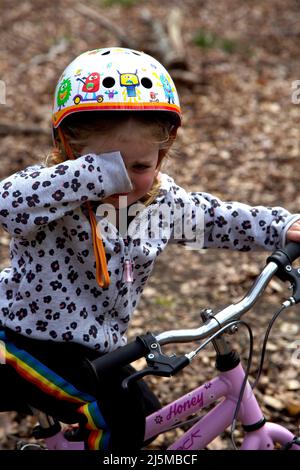 ragazza di 3 anni sulla sua moto, piangendo. REGNO UNITO Foto Stock