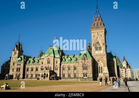 Ottawa, Ontario, Canada - 22 aprile 2022: Il blocco est degli edifici del Parlamento canadese visto dal prato di Parliament Hill con i visitatori. Foto Stock