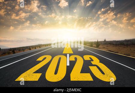 Concetto di nuovo anno. Anniversario dal 2022 al 2023. Testo 2023 scritto sulla strada in mezzo alla strada asfaltata al sorgere del sole.concetto di pianificazione e b Foto Stock