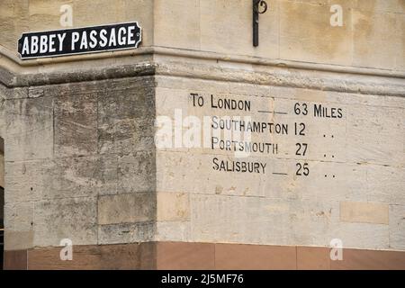 Milestone Marker scrittura con distanze da diverse città inglesi e un Abbey Passage strada segno sul lato del vittoriano Guildhall Winchester Foto Stock