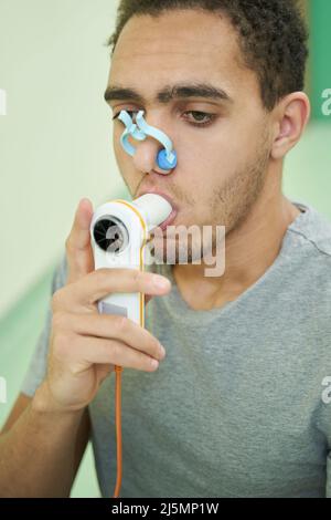 Persona che esegue il test di finczionalità polmonare con dispositivo di spirometria Foto Stock