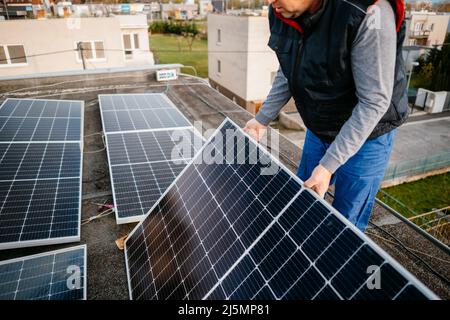 Lavoratore che installa pannelli solari. Energia alternativa in casa di famiglia. Foto Stock