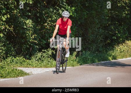 Giovane donna professionista bicyclist durante la corsa su strada, movimento continuo con massimo sforzo, vista ravvicinata. Foto Stock