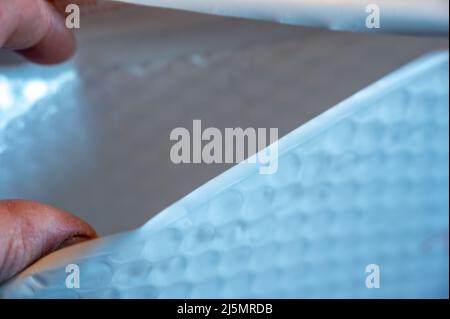 Messa a fuoco selettiva sulla mano che apre una busta imbottita. Foto Stock