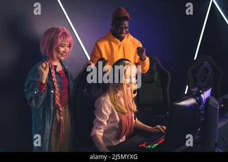 Carino hipster femminile caucasica che gioca video giochi, donna asiatica e uomo afro-americano che acclamano lo spazio di copia . Foto di alta qualità Foto Stock