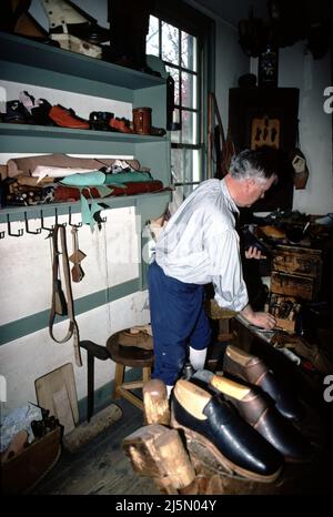 Williamsburg, California. USA 9/1987. Cordwainer era il titolo dato ai calzolai. Cobblers erano quelli che riparavano le scarpe. Il cobbler aveva cinque anni di formazione in meno rispetto ad un cordwainer. Le colonie americane, i ciottoli sono stati proibiti dalla proclamazione di fare le scarpe. I primi calzolai, conciatori e altri artigiani arrivarono a Jamestown nel 1607. Tra i molti talenti del fondatore principale della colonia John Smith, c’era quello del calzolaio – l’insediamento era parzialmente finanziato da un fiorente commercio di scarpe inglese. Foto Stock