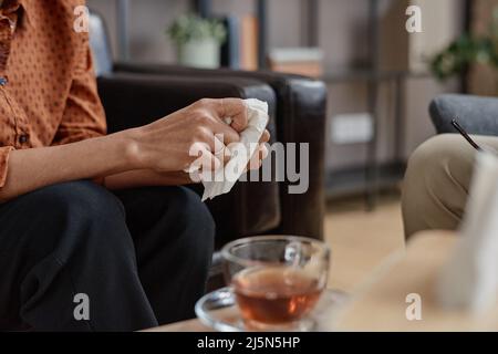 Primo piano orizzontale medio di una giovane donna adulta irriconoscibile che tiene tovagliolo di carta con appuntamento psicologo Foto Stock
