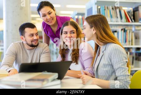 Simpatico gruppo di studenti in preparazione insieme per l'esame in una moderna biblioteca universitaria Foto Stock