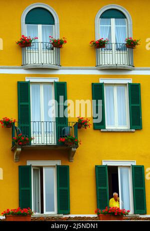 L'uomo a guardare fuori dalla finestra di hotel di Bellagio sul Lago di Como in Italia settentrionale Foto Stock