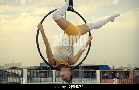 Donna in abbigliamento sportivo che fa Sky yoga sul tetto la sera quando il sole tramonta. Cura di sé e concetti di salute. Foto Stock