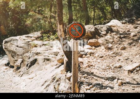 Non fumare paletto di legno su un sentiero di montagna. Cartello ecologico che vieta di fumare nella zona Foto Stock