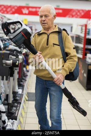 Uomo anziano che sceglie la felpa con cappuccio verticale nello showroom del negozio di elettrodomestici Foto Stock