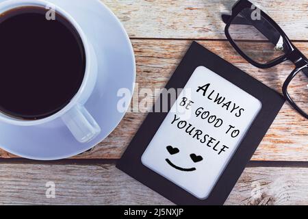 Citazione motivazionale sulla cornice della lavagna e tazza di caffè bianca sulla scrivania di legno - sia sempre buono a lei. Foto Stock