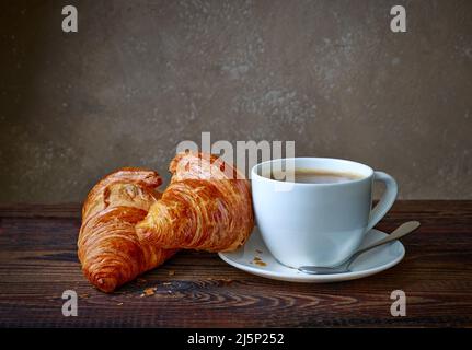 tazza di caffè e croissant su tavolo da cucina in legno Foto Stock