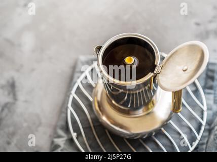 Caffè appena fatto in una caffettiera su sfondo grigio Foto Stock