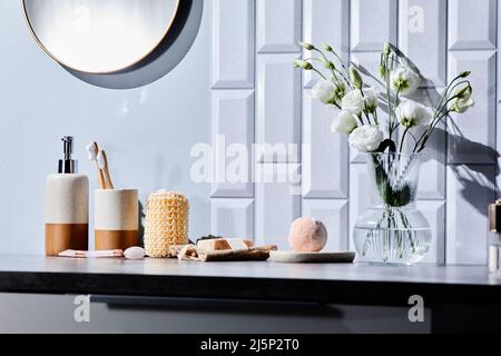 Prodotti di bellezza per la cura del corpo con fiori in vaso sul tavolo in bagno Foto Stock