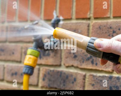 uomo con tubo flessibile per acqua ad alta pressione e accessorio per nebulizzazione acqua Foto Stock