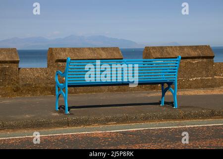 Sedile a panca dipinto di blu di fronte all'isola di Arran su una spianata costiera Foto Stock