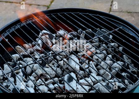 Barbecue pezzi di carbone fiammeggiante su un patio giardino Foto Stock