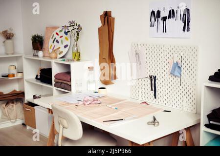 Carta con disegno di cucito e schizzi sulla scrivania in studio di moda di designer Foto Stock