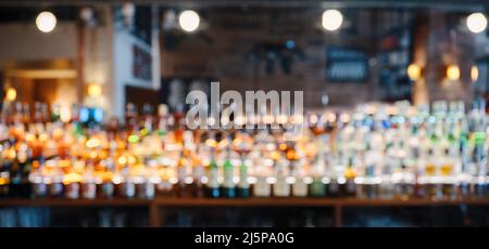 Sfondo bar o pub con bottiglie di liquore sfocate sugli scaffali. Foto Stock