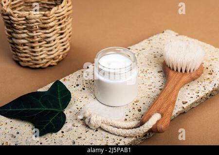 Crema cosmetica in un vaso e pennello viso su pietra naturale. Spa e benessere, concetto zero rifiuti. Foto Stock