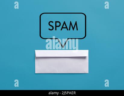 Busta bianca con la parola spam su sfondo blu. Concetto di spam o posta indesiderata. Foto Stock