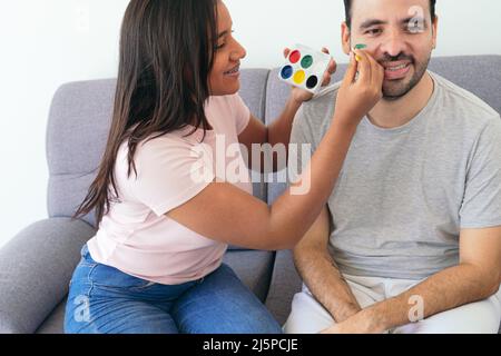 Donna che dipinge la bandiera brasiliana sul volto di un amico Foto Stock