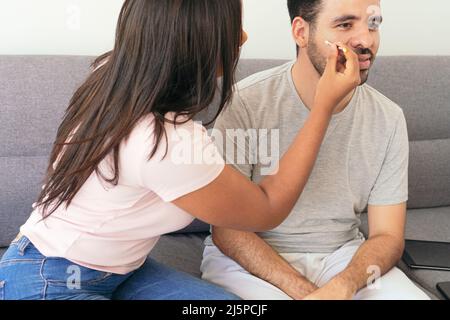 Donna che dipinge la bandiera brasiliana sul volto di un amico Foto Stock