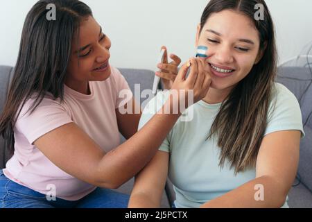 Donna che dipinge la bandiera argentina sul volto di un amico Foto Stock