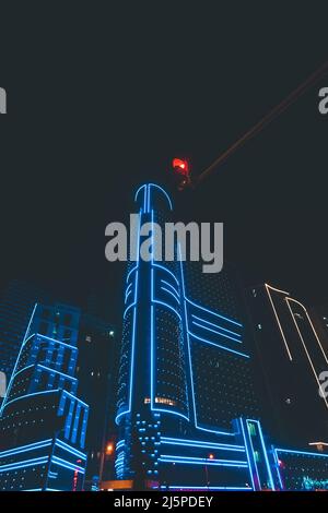 Primo piano di un moderno edificio a più piani di colore blu brillante. Vita notturna della città Foto Stock