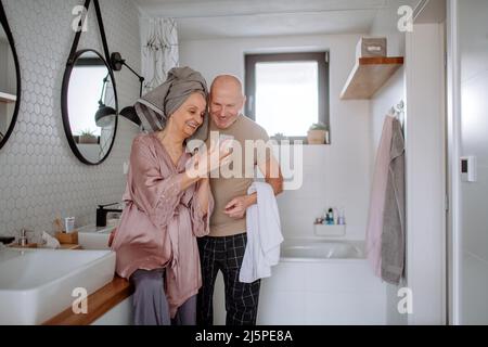 Coppia anziana innamorata in bagno, con smartphone, concetto di routine del mattino. Foto Stock