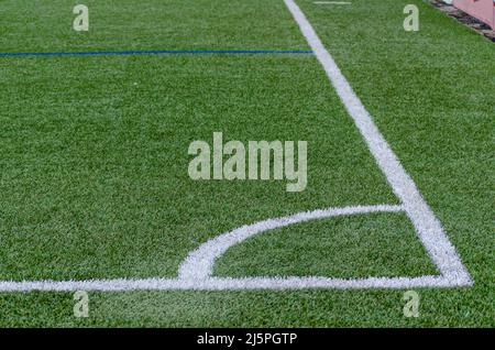 Linea d'angolo di un campo di calcio artificiale di erba sintetica blu Foto Stock