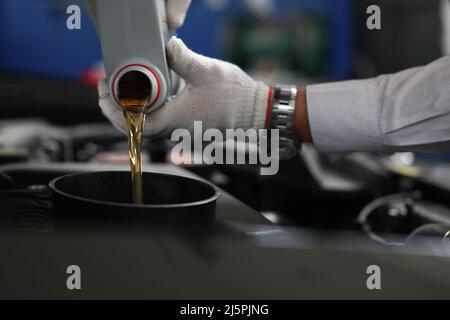 Rifornimento e versamento dell'olio del meccanico automatico nel motore della vettura Foto Stock