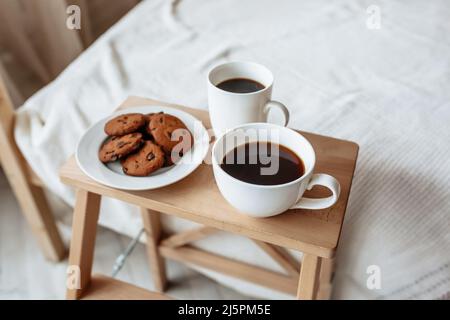 Colazione in camera. Caffè caldo con biscotti di farina d'avena e cioccolato su un vassoio di legno Foto Stock