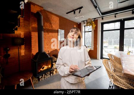 Donna in piedi con un tablet digitale in un accogliente soggiorno in stile loft Foto Stock
