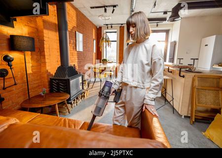 Donna asiatica che aspira il divano con pulitore per tappezzeria per  sbarazzarsi di polvere e macchie Foto stock - Alamy