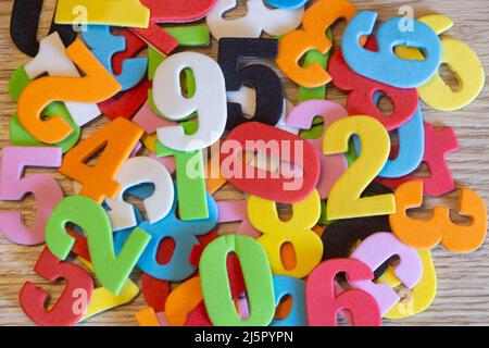 Numeri multicolore in schiuma su sfondo di legno Foto Stock