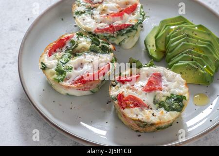 Muffin all'uovo con pomodoro, spinaci e formaggio Foto Stock