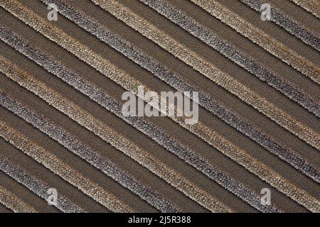 La texture di un tessuto in corduroy di cotone beige naturale con strisce chiare, posizionato diagonalmente. Le creste della corturoia sulla diagonale Foto Stock