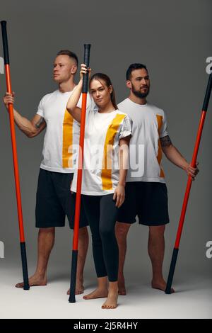 Le persone si levano in piedi insieme e praticano i bastoni. Maestri di Karate in posa con bastoni nello studio insieme. Foto Stock