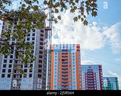 Un cantiere con quattro nuovi e colorati edifici alti e una gru sullo sfondo del cielo blu. Nuovo distretto in costruzione a Kiev Foto Stock