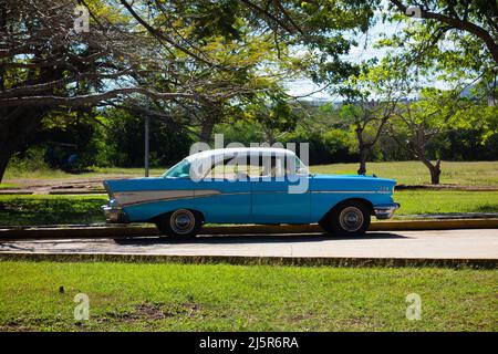 HOLGUIN, CUBA - 16 FEBBRAIO; 2020 auto classica blu e bianca parcheggiata sotto un albero Foto Stock