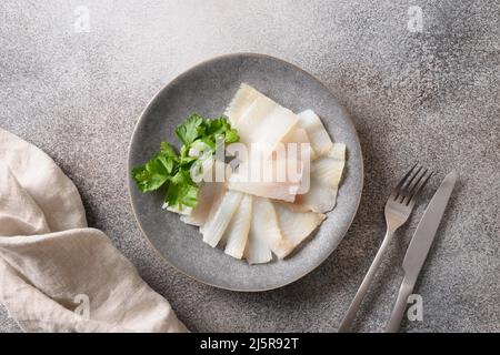 Deliziose fette di halibut affumicate servite con prezzemolo su sfondo grigio. Vista dall'alto. Spazio di copia. Foto Stock