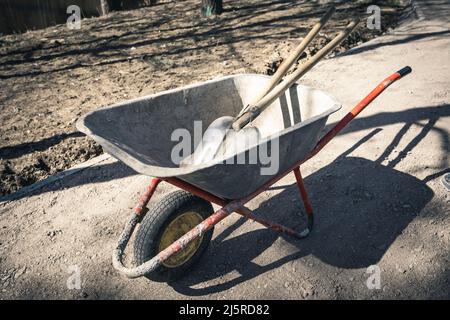 carriola di lavoro vecchia e affidabile con pale in cantiere Foto Stock