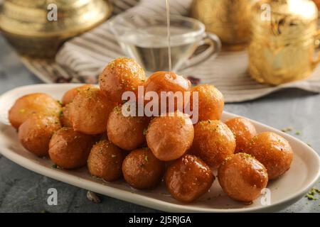 luqaimat o lokma. Lokma fritto di fresco (luqma - arabic) impaccato alto un dessert medio orientale popolare di palle di pasta fritte profonde poi rivestite in sug Foto Stock