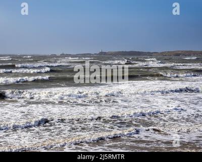 Onde soffocate dai venti della forza di tempesta a Newborough su Anglesey, Galles, Regno Unito, guardando verso Llanddwyn Island. Foto Stock