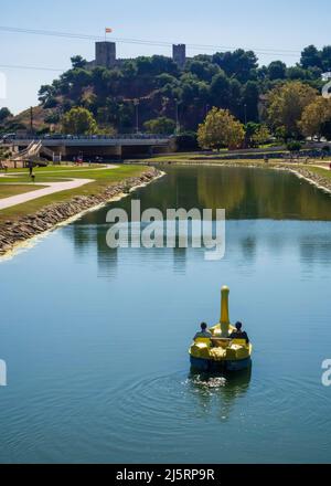 Due ragazze che cavalcano un pedalo sul fiume Fuengirola con il castello di Sohail sullo sfondo. Foto Stock