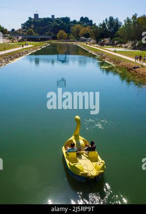 Due ragazze che cavalcano un pedalo sul fiume Fuengirola con il castello di Sohail sullo sfondo. Foto Stock